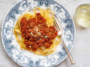 A beautiful fast bolognese sauce on a blue patterned plate with noodles and fork.