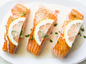 three cooked salmon with lemon on a white plate