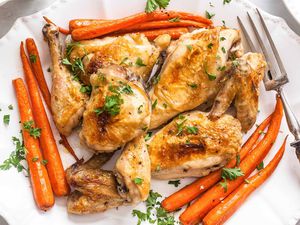 Best Baked Chicken Recipe chicken on white plate with carrots and herbs