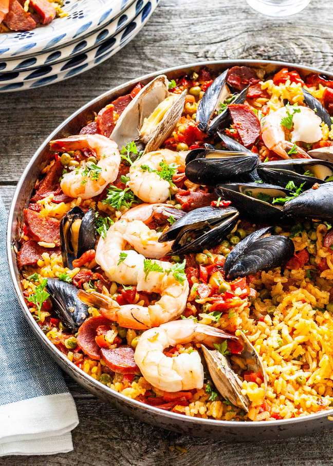 Paella recipe with seafood, cooked on the grill and served in a skillet
