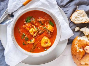 Easy Tortellini Soup - white bowl with tomato soup, fresh basil and cheese filled tortellini