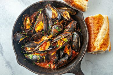 Mussels in tomato sauce recipe - overhead photo of mussels in cast iron pan with bread