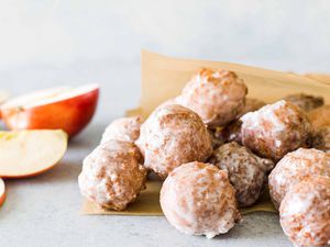 The best apple cider donuts piled up on the counter with sliced apples behind them