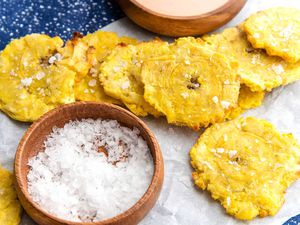 Air Fryer Tostones on parchment paper with a bowl of salt nearby.