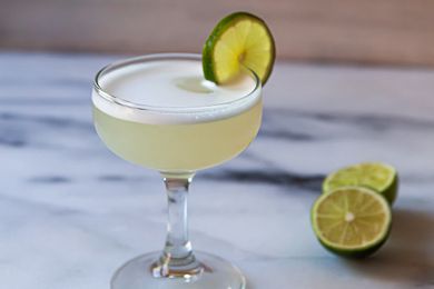 A chilled coupe with a frothy gin cocktail to show what a gimlet is.