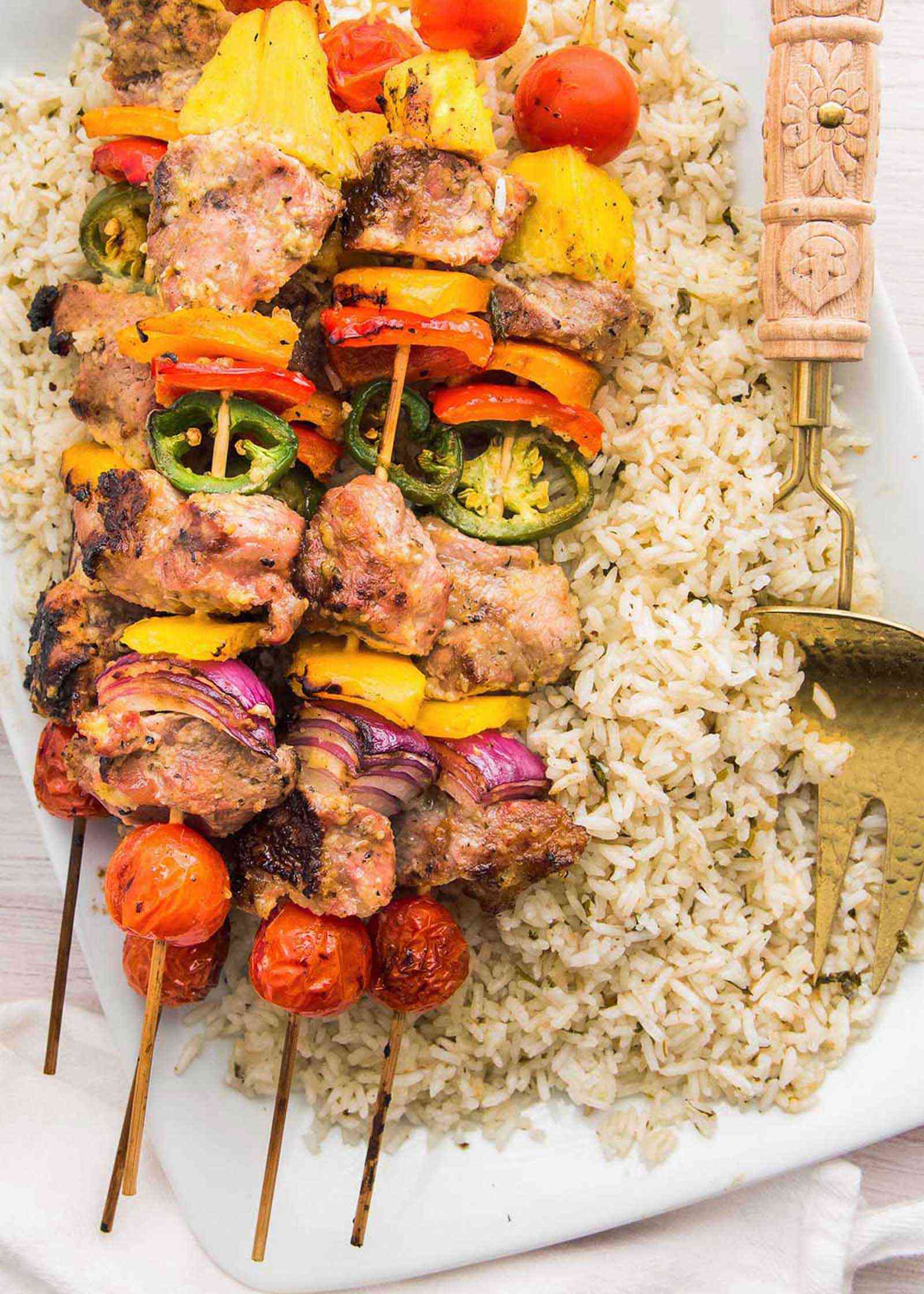 Pork skewers with vegetables over a plate of rice