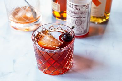 Vieux carre in a whiskey glass with ingredients to make the cocktail behind it.
