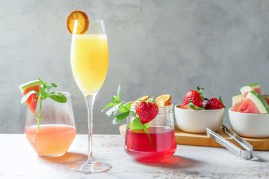 A variety of mimosas on a table and garnished with fruit for a DIY Mimosa Bar.