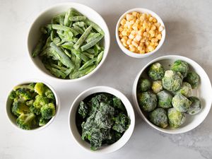 Frozen corn green beans broccoli brussels sprouts in white bowls