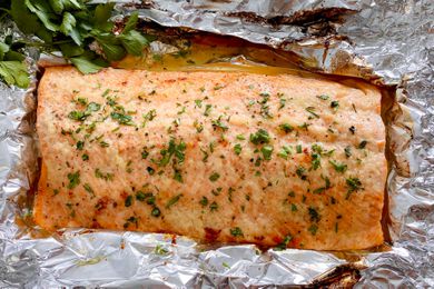 Honey Garlic Butter Roasted Salmon topped with herbs and set on foil.
