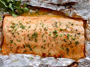 Honey Garlic Butter Roasted Salmon topped with herbs and set on foil.