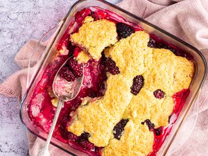 Overhead view of easy blackberry cobbler in a baking dish with a spoon set where a serving was removed.