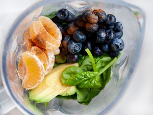 Overhead view of fresh fruit in a blender to make a blueberry smoothie recipe.