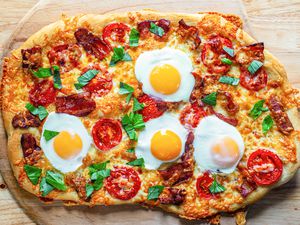 Overhead view of a breakfast pizza topped with eggs.