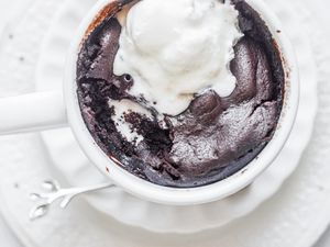 Overhead view of a brownie in a white mug topped with ice cream.