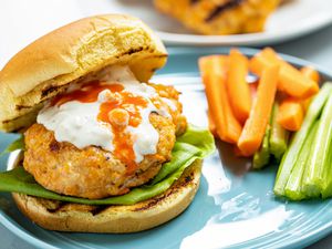 The top bun set to the side of the BEST spicy buffalo chicken burger.