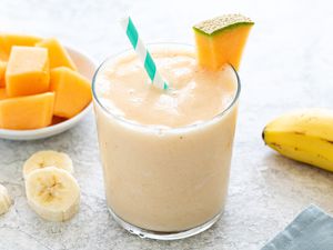 Simple cantaloupe smoothie in a glass and garnished with a slice cantaloupe.