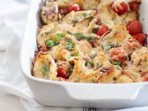 Stuffed shells with tomatoes, mozzarella, and basil in a casserole dish