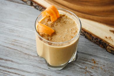 Side view of a creamy carrot cake smoothie in a glass.