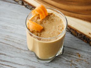 Side view of a creamy carrot cake smoothie in a glass.