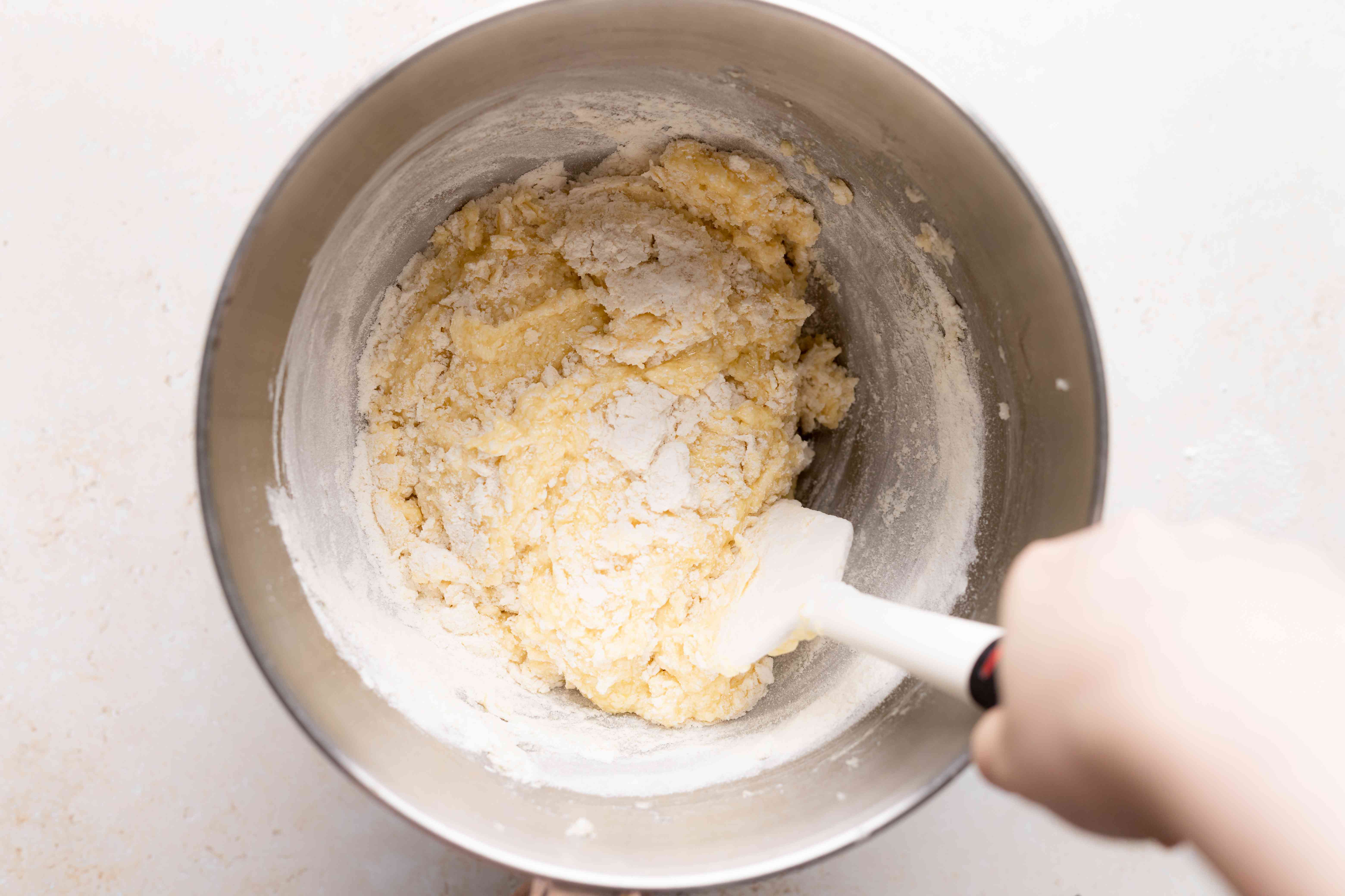 Mixing in dry ingredients for a butter cake with fresh cherries