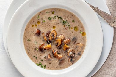 Chestnut mushroom soup in a white bowl with a white plate underneath.