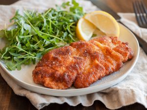 chicken schnitzel on plate with arugula and lemons