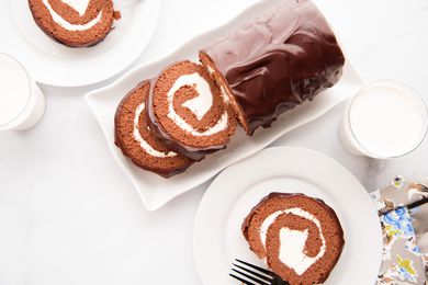 Overhead view of a chocolate cake roll and a plate with a slice on it.