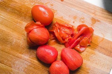 Tomatoes and tomato peel on wood cutting board