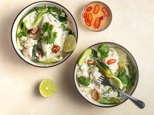 Overhead view of two bowls of Coconut poached cod with ginger and lime served with lime and rice.