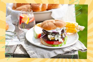 Plate on a table with a burger, corn on the cob, and slice of watermelon