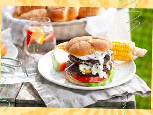 Plate on a table with a burger, corn on the cob, and slice of watermelon
