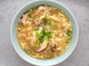 Bowl of egg drop soup with mushrooms and spring onions