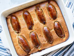 Overhead view of toad in the hole in a baking dish with a blue striped linen underneath.