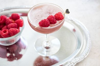 French Martini in a Glass Garnished with Raspberries on a Tray with a Bowl of Raspberries