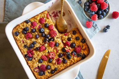 Overhead view of a baking pan with Baked Berry Oatmeal topped with extra berries with a serving removed from the dish.