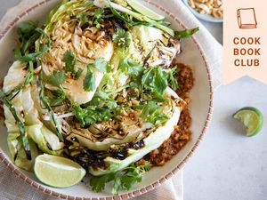 Grilled cabbage with peanut satay sauce on a plate with toppings in small bowls around it.
