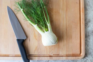 Fennel bulb and fronts with chef's knife on cutting board