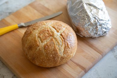 Bread loaf next to aluminum foil wrapped loaf