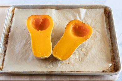 Two roasted halves of butternut squash on a sheet pan
