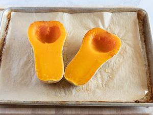 Two roasted halves of butternut squash on a sheet pan
