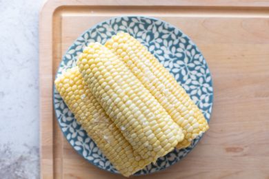 Three ears of cooked corn on the cob on a blue flower plate