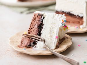 Slice of Ice Cream Cake on a Small Plate with a Fork with More Cake in the Background