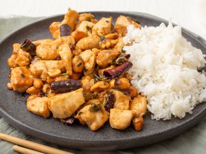 Side view of a plate of kung pao chicken with rice.