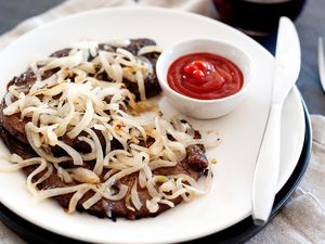 A plate of liver and onions and ketchup.