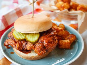 Nashville hot chicken sandwich with pickles and served on a plate.