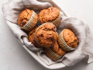 Classic pumpkin muffins nestled in a cream colored linen and oval bowl.