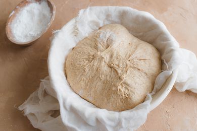 Dough in a towel lined bowl to make spiced sourdough bread shaped like a pumpkin