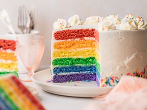Rainbow Layer Cake on a Plate with a Portion Cut Out, Surrounded by More Cake