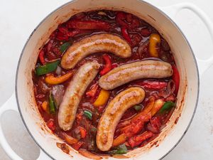 Overhead view of a dutch oven with polish sausage recipes with peppers and onions inside.